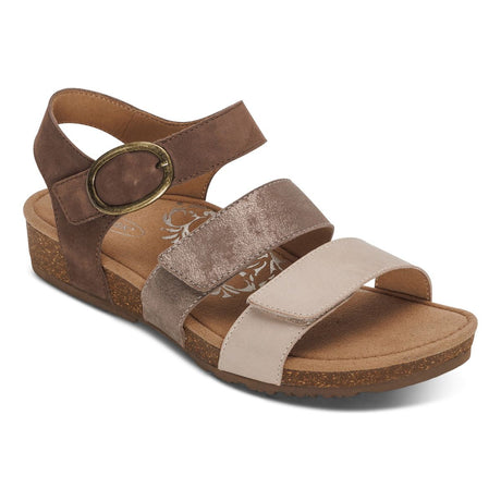Taupe leather sandal with decorative cutouts and two adjustable hook-and-loop straps, contoured footbed with arch and forefoot support, and a low cork-rubber outsole designed for daily comfort and stability. Style #SC562