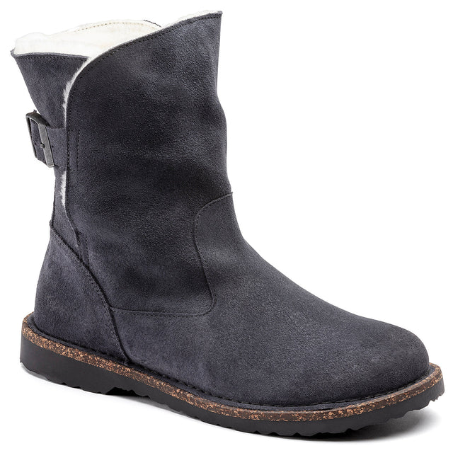 A style image of the Uppsala Shearling Boot, which is a dark grey boot with a suede and shearling upper, a contoured cork footbed, and a rubber outsole.
