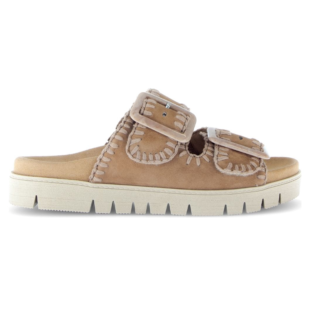 Women’s brown suede slide sandal with two large buckles, whipstitch detailing, and a thick white lug sole. Style #741.14