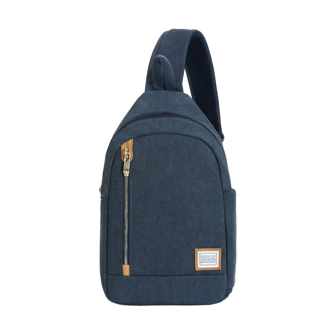 A navy indigo canvas sling bag with a vertical front zipper and tan leather accents. Style # 33604-350