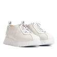 Off-white leather low-top sneaker with a flared wedge sole and lace-up front, blending sporty comfort with minimalist European design. Style #A2424-0350